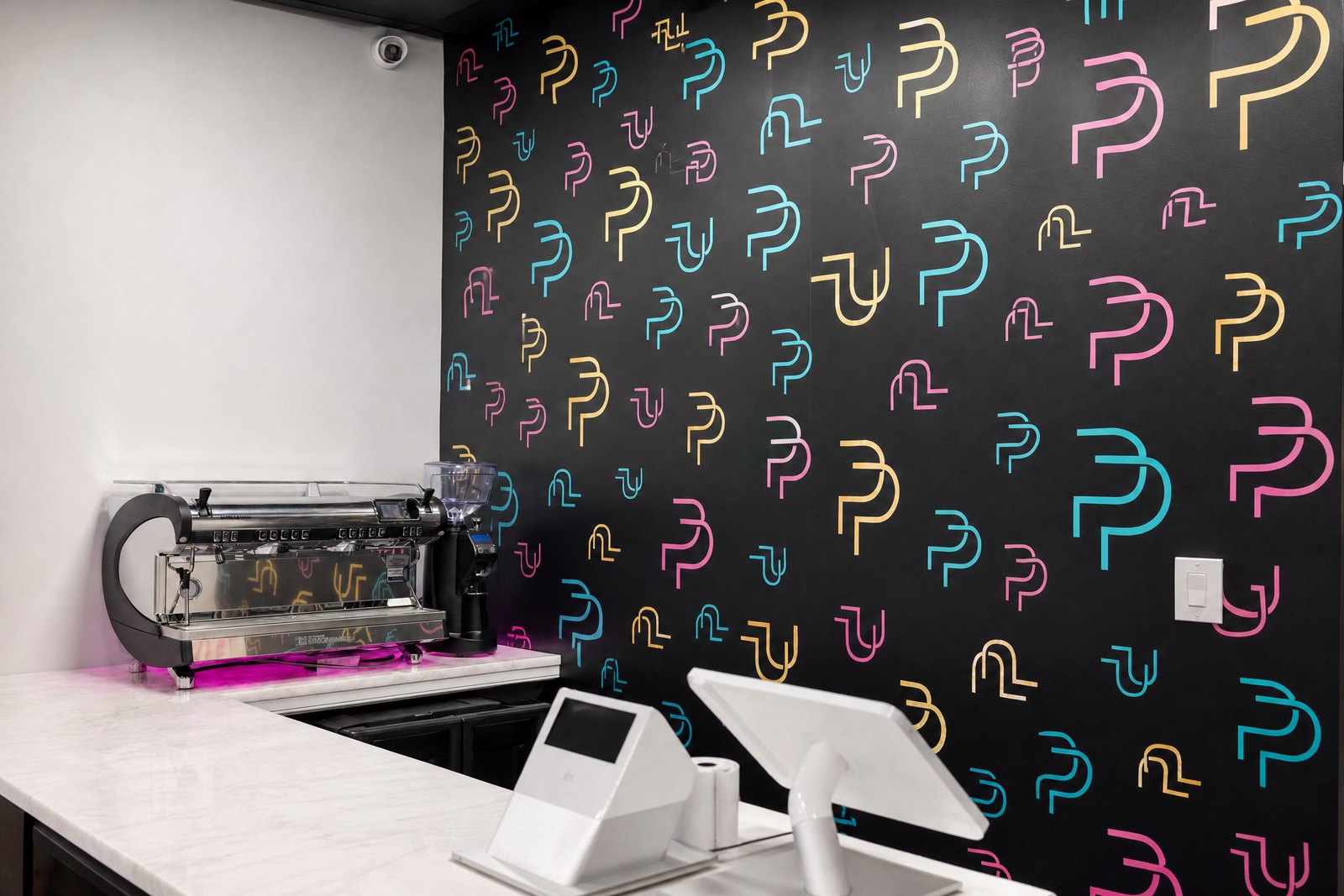 Plated Perfection counter with espresso machine and patterned logo wall